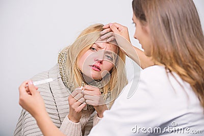 Her fever makes her uncomfortable. Doctor visiting unhealthy woman at home. Medical doctor examining patient. Primary Stock Photo