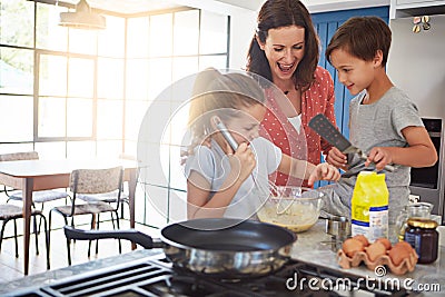 Her kids love baking. a mother baking with her children in the kitchen. Stock Photo