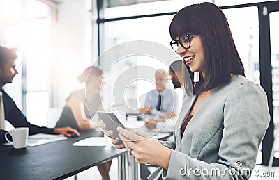 Her tablet makes note-taking easy. an attractive young businesswoman using her tablet during a meeting in the boardroom. Stock Photo