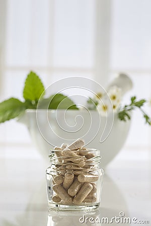 Herbal medicine pills and mortar over bright background Stock Photo