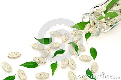 Herbal supplement pills and fresh leaves spilling Stock Photo