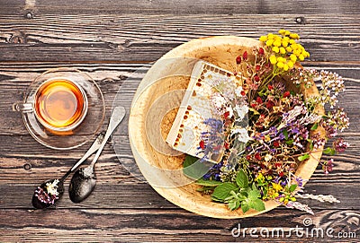 Herbal tea cup, healing herbs and honey in a wooden bowl on a wooden table Stock Photo