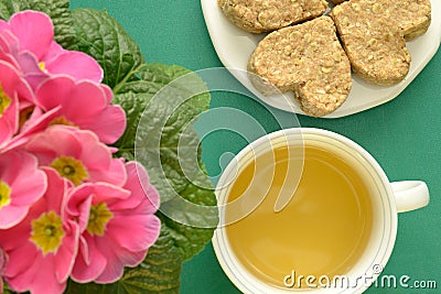 Herbal tea in cup Heart-shaped oatmeal cookies Pink flowers Stock Photo