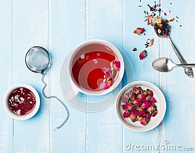 Herbal tea, dry roses and jam on blue colored table Stock Photo