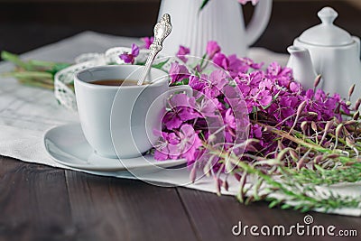 Herbal tea in a glass cup, fresh flowers fireweed against the da Stock Photo