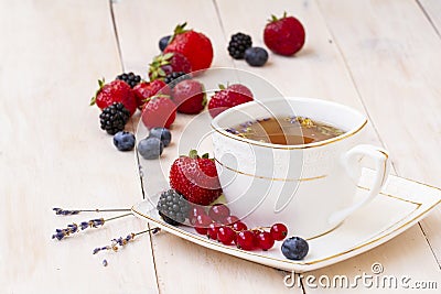 Herbal tea with lavender and mint, fresh strawberries, blackberries and blueberries on a white wooden table. Berry tea Stock Photo