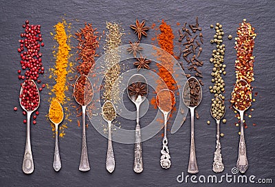 Herbs and spices in silver spoons on black stone background Stock Photo