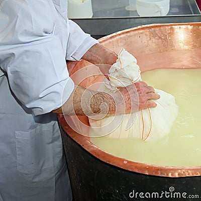 herdsman Cheesemaker collects cheese from the copper cauldron w Stock Photo