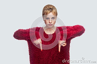 Here and right now. Portrait of angry young blond woman in red blouse standing and commanding to be here quickly as possible Stock Photo