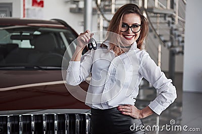 Here`s your keys. Woman in eyewear and white shirt stands near the red automobile Stock Photo