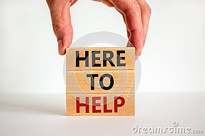 Here to help symbol. Male hand builds stack from blocks with words `here to help`. White table. Beautiful white background. Copy Stock Photo