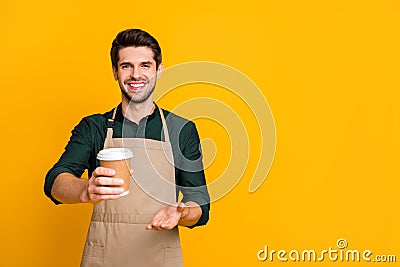 Here your latte. Portrait of positive cheerful guy student work part-time in coffee bar shop give to client paper card Stock Photo