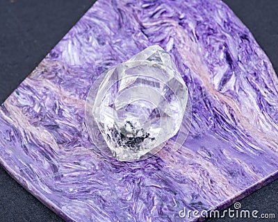 Herkimer Diamond placed on top grade Charoite polished slab from Sakha Republic, Siberia, Russia. On black background. Stock Photo