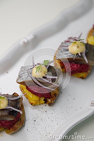 Herring canapes with pickled onions and baked potatoes. Appetizer on a platter close-up Stock Photo