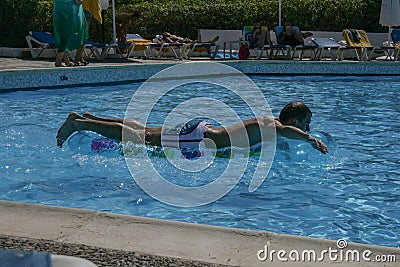 09.19.2008, Hersonissos, Crete, Greece. young guy swims in the pool on a water mattress. Editorial Stock Photo