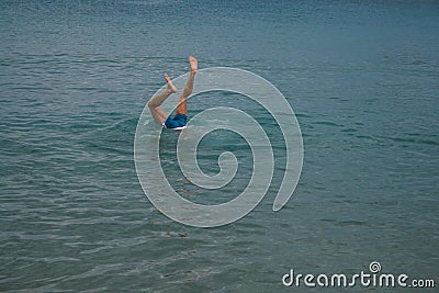 09.20.2008, Hersonissos, Crete, Greece. A young man `s legs over the water. A guy diving into the water. Editorial Stock Photo