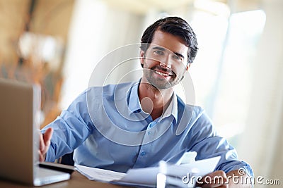 Hes a financial whizz. A handsome young businessman working on his laptop at his desk. Stock Photo