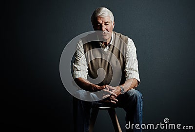 Hes got a lot on his mind. Studio shot of a handsome mature man looking thoughtful while sitting on a stool against a Stock Photo