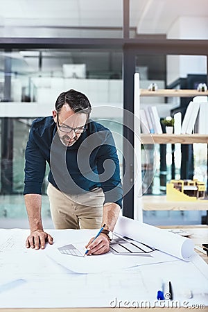 Hes a problem solver. a mature male architect working on a design in his office. Stock Photo