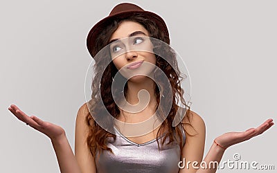 Hesitant young woman purses lower lip, spreads palms with clueless expression, being unaware, cannot make choice Stock Photo