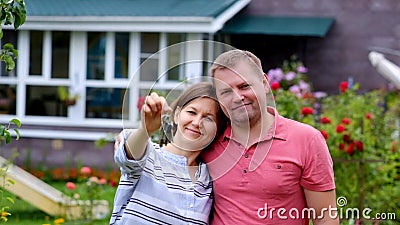 Het kopen huisconcept Vrouw met haar sleutels van de echtgenootholding van nieuw huis Het kopen huisconcept Vrouw met haar sleutels van de echtgenootholding van nieuw huis