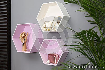 Hexagon shaped shelves with different stuff on wall. Interior design Stock Photo