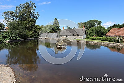 The hexagonal duck house on the village pond at East Quantoxhead in Somerset, England. Thatched cottages can be seen in the Stock Photo