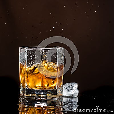 Hexagonal glass of whiskey with ice on a dark background and a number of real ice cubes Stock Photo