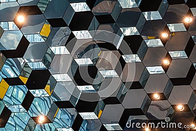 Hexagonal mirrored tiles with lights creating dynamic reflective ceiling design Stock Photo