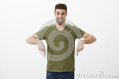 Hey hurry and check out promo. Portrait of excited overhwhelmed happy young bearded guy smiling amazed and pointing down Stock Photo