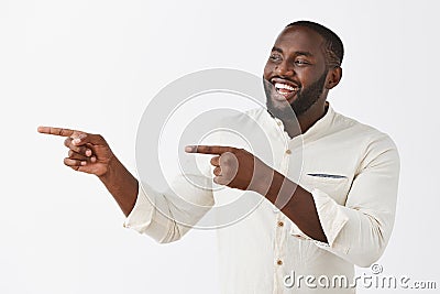 Hey mate what is up. Pleased happy and successful dark-skinned party host in white formal shirt pointing and looking Stock Photo