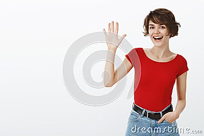 Hey whats up. Attractive sociable cheerful friendly european girl short haircut waving raised palm say hi hello greeting Stock Photo