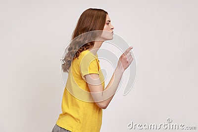 Hey you, be careful. Side view of strict bossy woman of young age with brown hair in yellow casual T Stock Photo