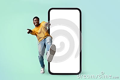 Hey you, check this website. Excited black man standing near huge smartphone with blank screen, mock up Stock Photo