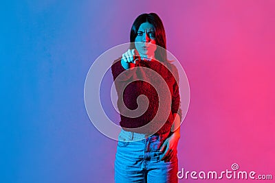 Hey you! Neon light portrait of strict bossy woman frowning displeased angry and pointing finger to camera Stock Photo