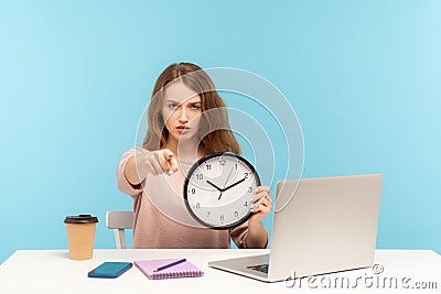 Hey you, time to work! Strict bossy serious woman, office employee sitting at workplace, pointing to camera Stock Photo