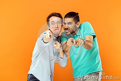 Hey you! Two expressive comic, grimacing at camera. Pointing fin Stock Photo