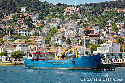 The blue fishing boat is at the pier on the island. Sea, white houses on the slopes of the island. Travel to Heybeliada, Adalar, Stock Photo