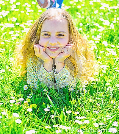 Heyday concept. Girl on smiling face spend leisure outdoors. Girl lying on grass at grassplot, green background. Child Stock Photo