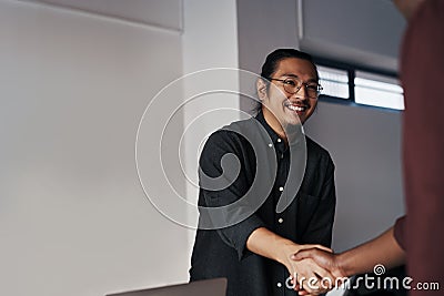 Hi, welcome. two young businessmen greeting each other with a handshake before sitting down in the office. Stock Photo