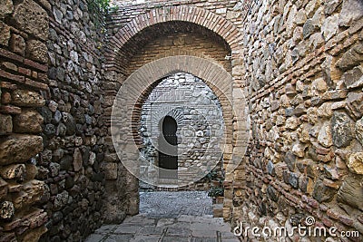 Hidden stone passageway in Malaga fortress with archs and gate Stock Photo