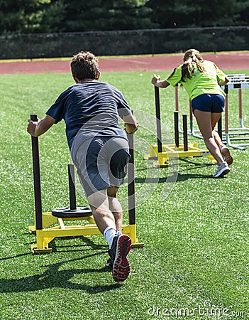 Hifh school boy and girl pushing heavy sled across field Editorial Stock Photo