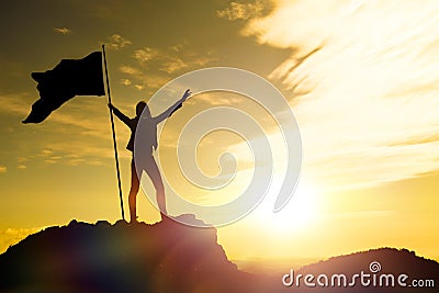 High achievement, silhouettes of the girl, flag of victory on the top of the mountain, hands up. Stock Photo