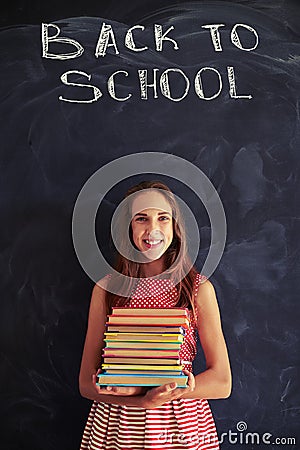 High achiever schoolgirl standing with books against blackboard Stock Photo