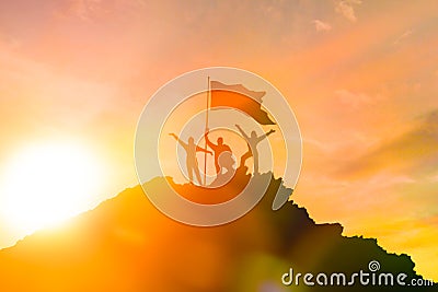 High achiever, silhouettes of three people holding on top of a mountain to raise their hands up. Stock Photo