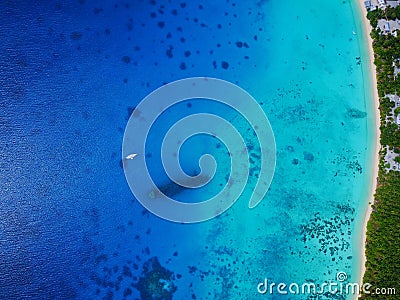 High aerial view of a sunken WWII ship wreck with an anchored yacht and village on an island Stock Photo