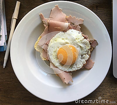 High angle close up over a plate with a sunny side up egg abd ham next to a pen Stock Photo