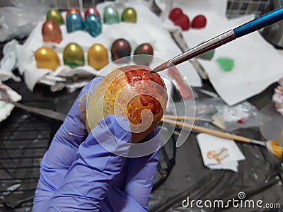High angle closeup shot of a person coloring Easter eggs on a white fabric Stock Photo