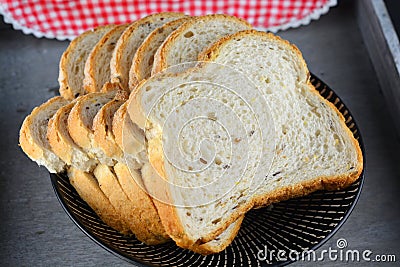 High angle closeup shot of a stack of sliced white bread in a plate next to a checkered tablecloth Stock Photo