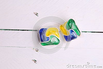 High angle closeup shot of two dishwasher capsules on a white wooden table Stock Photo